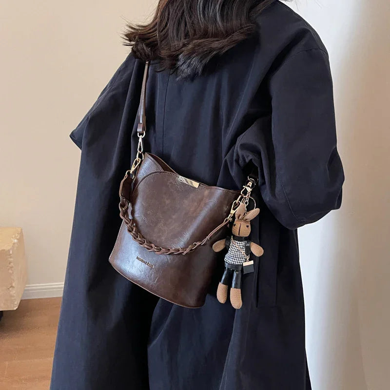 Woman wearing black coat with brown leather shoulder bag and bunny keychain accessory