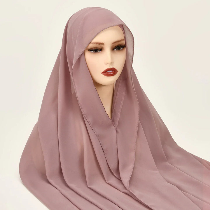 Mannequin head wearing mauve pink chiffon hijab with soft folds on beige background