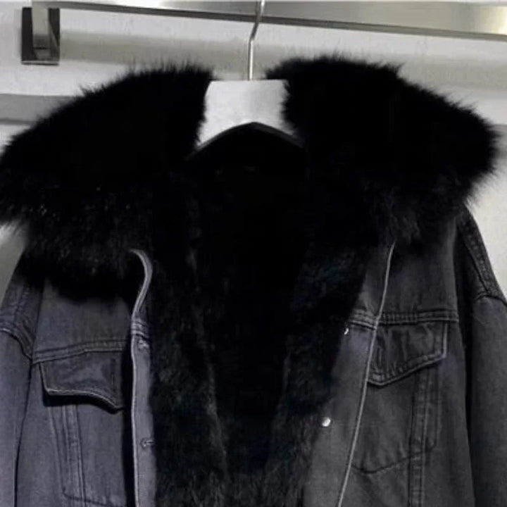 Black denim jacket with large black faux fur collar hanging on a hanger