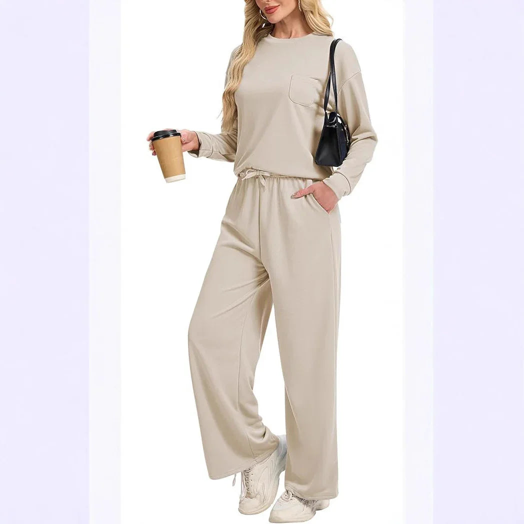 Woman wearing beige long-sleeve top and matching wide-leg pants holding coffee cup, black shoulder bag, white sneakers