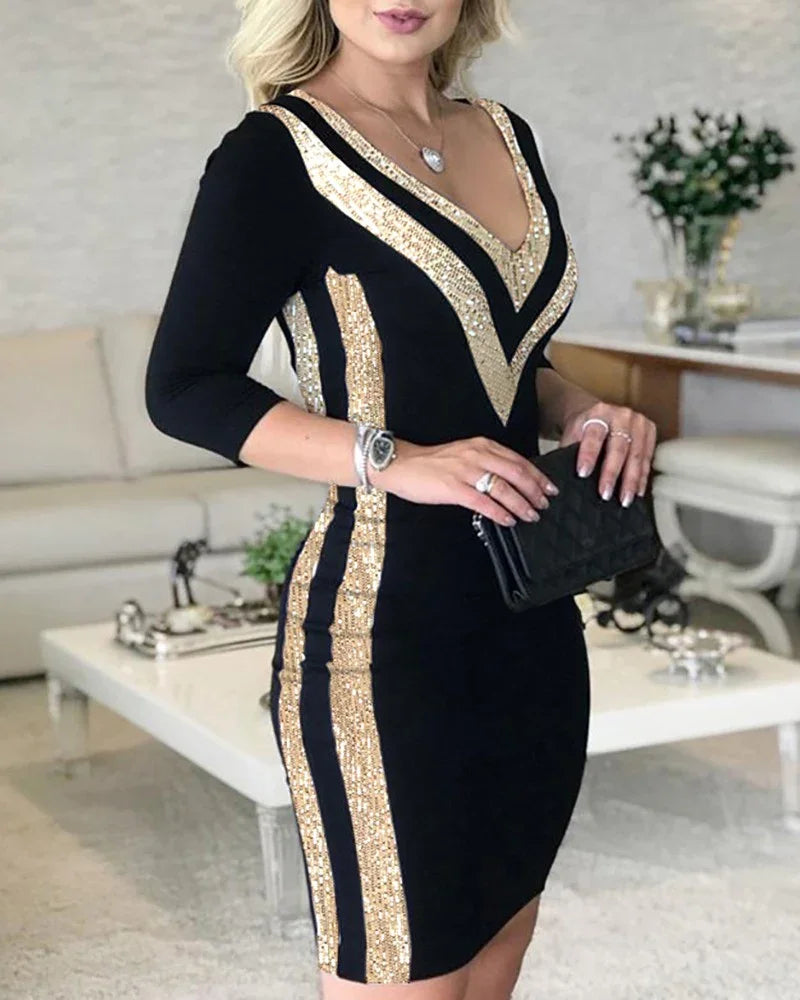 Woman wearing black bodycon dress with gold sequin stripes holding black clutch in modern living room