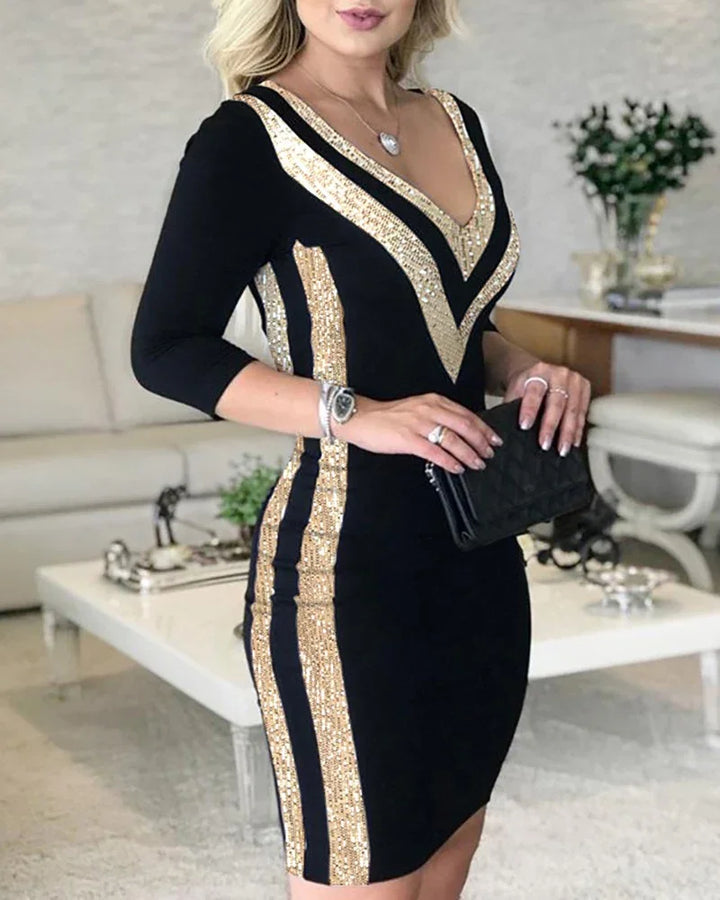 Woman wearing black bodycon dress with gold sequin stripes holding black clutch in modern living room