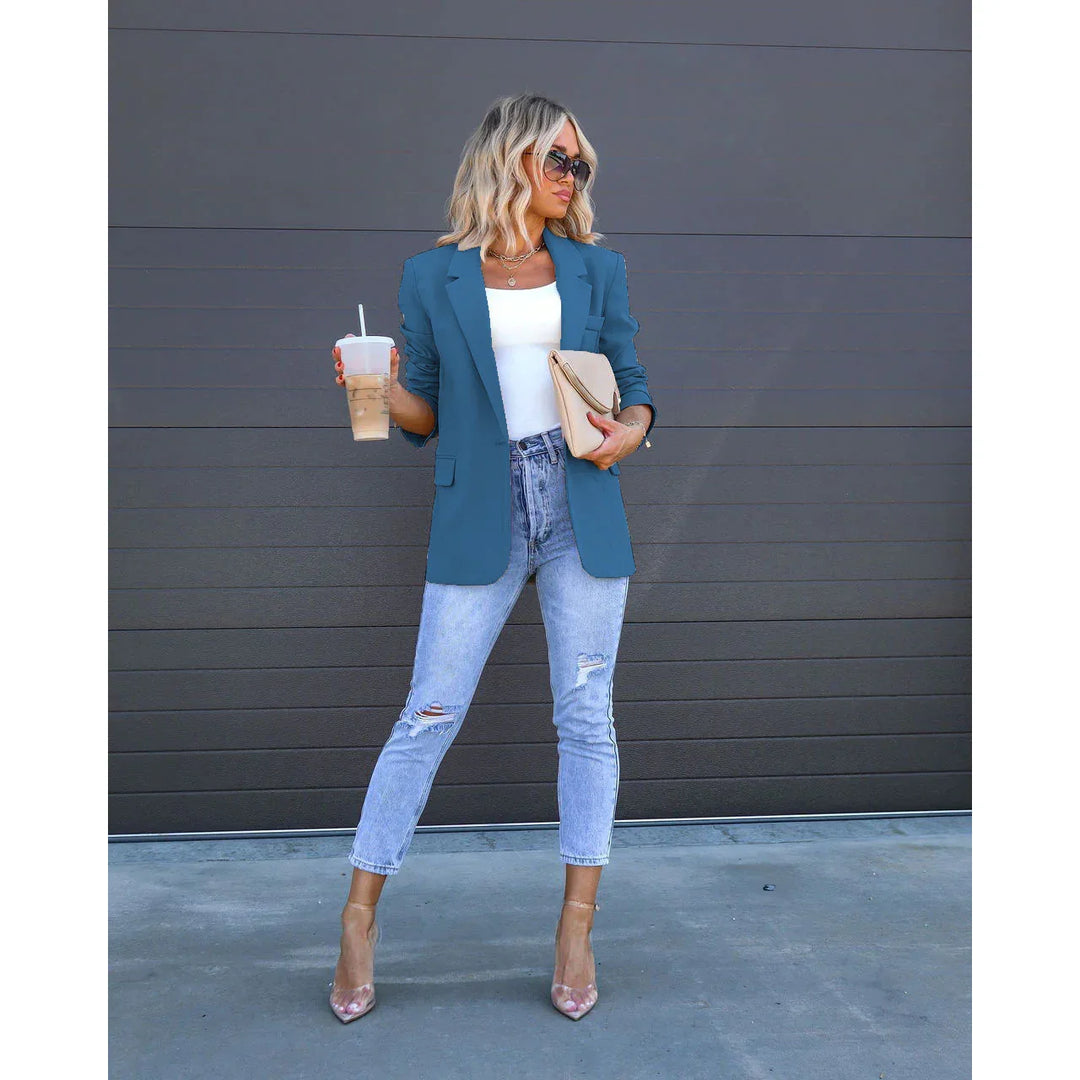 Stylish woman in blue blazer, white top, ripped jeans, clear heels, holding iced coffee and beige clutch