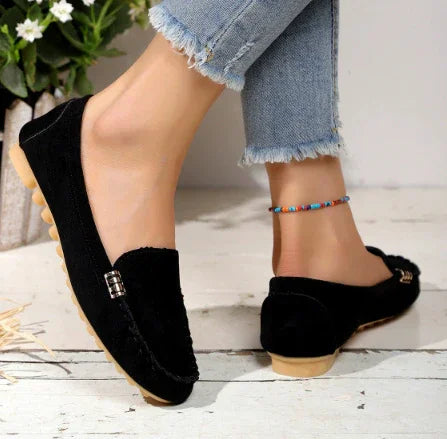 Black suede loafers with silver buckle detail worn with frayed hem jeans and a colorful ankle bracelet