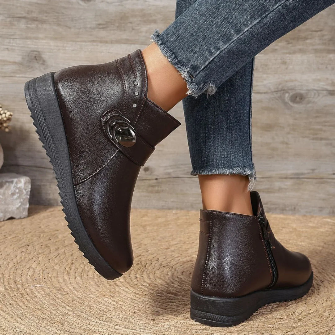 pair of dark brown leather ankle boots with decorative button detail worn with frayed hem jeans