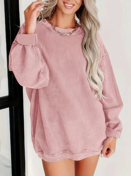 Woman wearing oversized pink corduroy sweatshirt with long puff sleeves and silver chain necklace