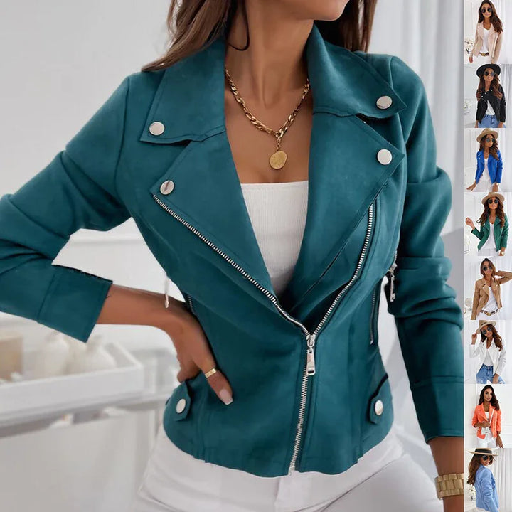 Woman wearing teal faux suede biker jacket with silver buttons and zipper, paired with white top and pants