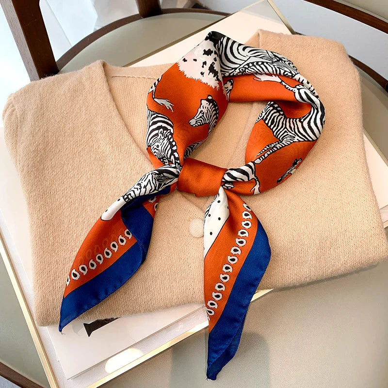 Beige wool sweater with orange and blue zebra print silk scarf on white tray