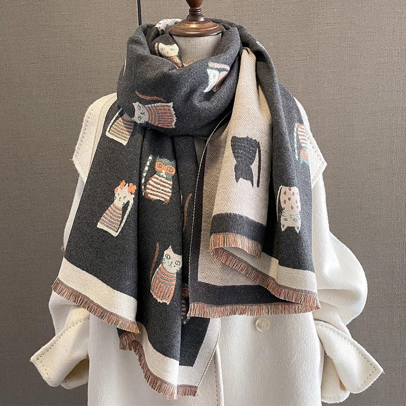 Cozy gray scarf with whimsical cat patterns draped over cream wool coat on mannequin