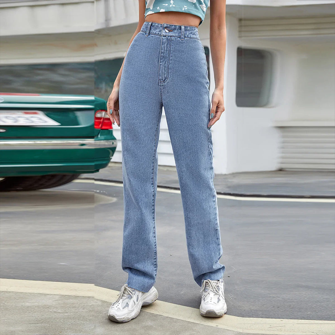 Woman wearing high-waist straight-leg light blue jeans and white sneakers outdoors
