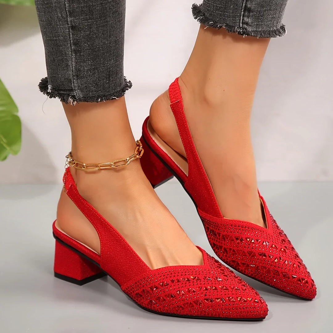 Close-up of feet wearing red suede slingback heels with block heels and rhinestone details