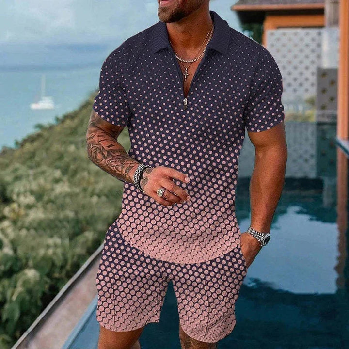 Man wearing pink and black polka dot short sleeve shirt and matching shorts by a pool with tropical background