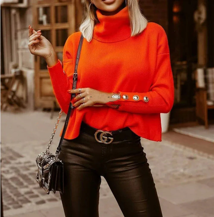 Woman wearing bright orange turtleneck sweater with button details and black leather pants in urban street setting