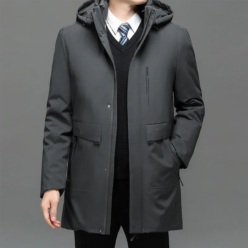 Man wearing black hooded winter parka over formal shirt and tie on gray background