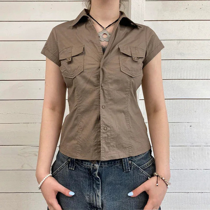 Woman wearing fitted short-sleeve brown button-up shirt with chest pockets and denim jeans