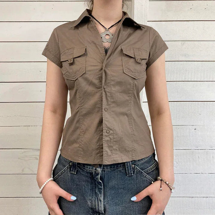 Woman wearing fitted short-sleeve brown button-up shirt with chest pockets and denim jeans