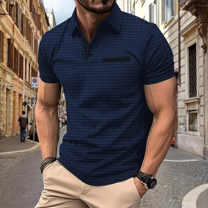 Man wearing navy blue textured polo shirt and beige pants on cobblestone street