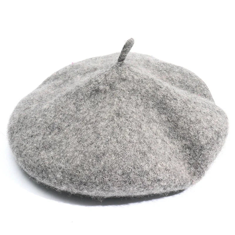 Grey woolen beret hat with a small top stalk on a white background