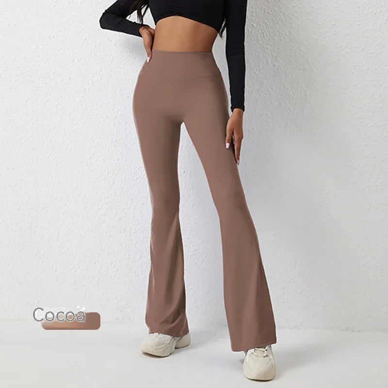 Woman wearing cocoa-colored high-waisted flare pants and black crop top against white wall