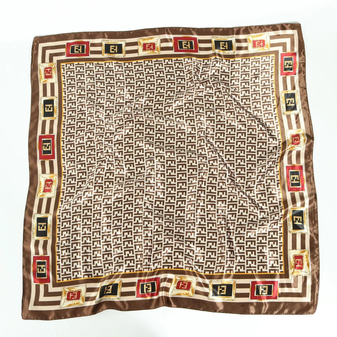 Brown and beige silk scarf with repeating geometric pattern and framed logo squares in red, black, and gold