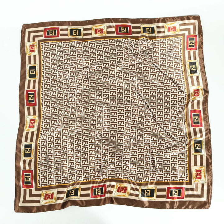 Brown and beige silk scarf with repeating geometric pattern and framed logo squares in red, black, and gold