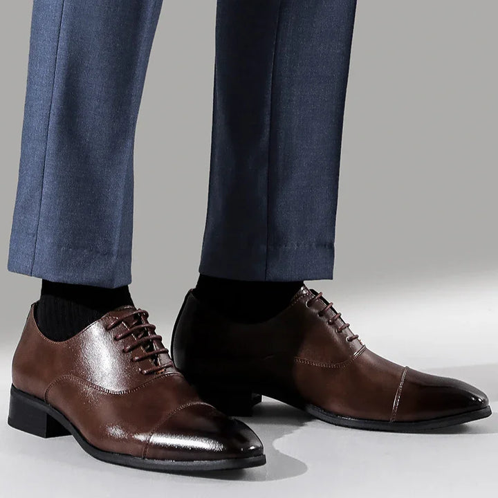 men's polished brown leather dress shoes paired with blue formal trousers and black socks