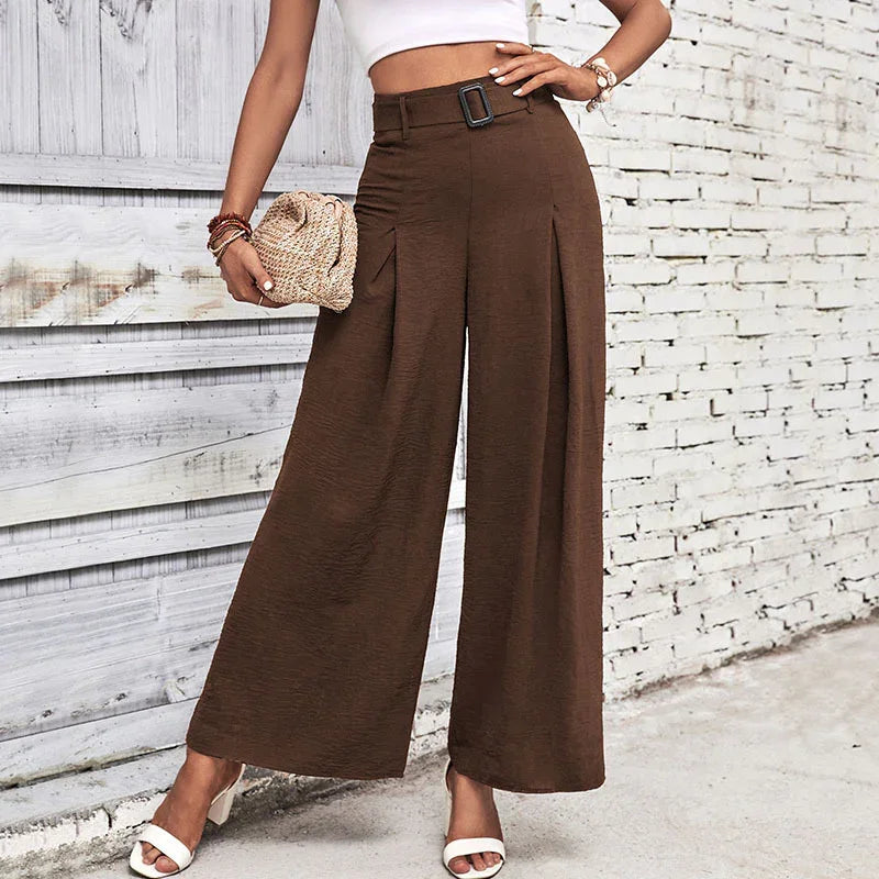 Woman wearing high-waisted brown wide-leg pants with a belt, white crop top, and white sandals