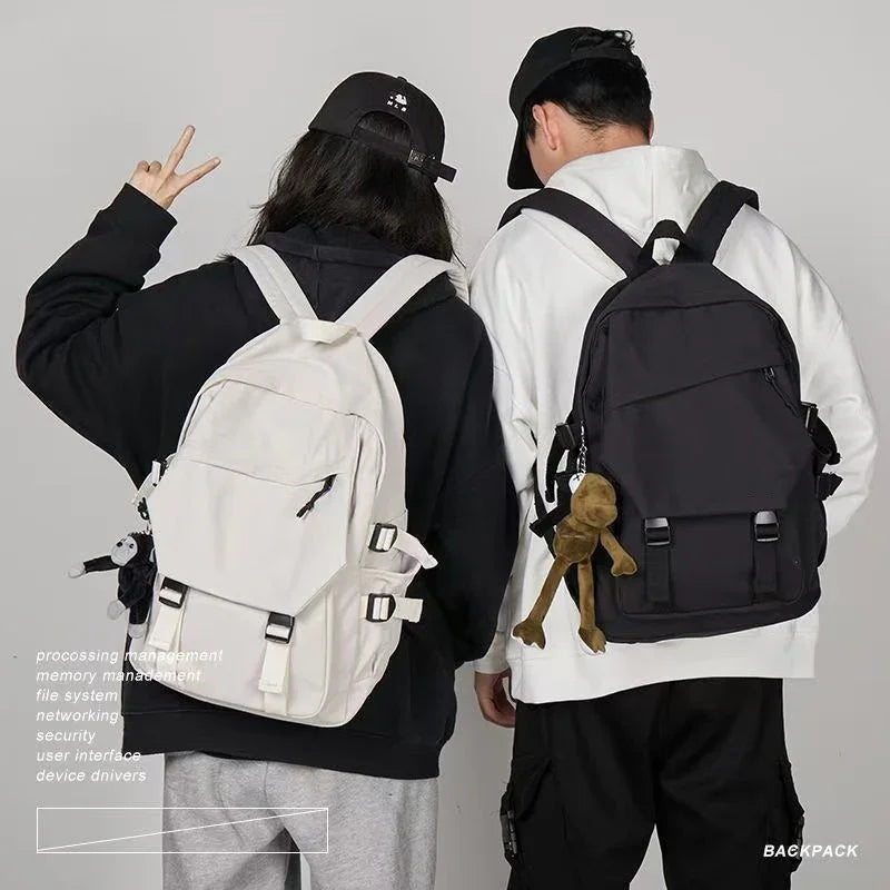 Two people wearing black and white backpacks with casual streetwear and black caps against gray background