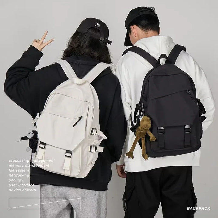 Two people wearing black and white backpacks with casual streetwear and black caps against gray background