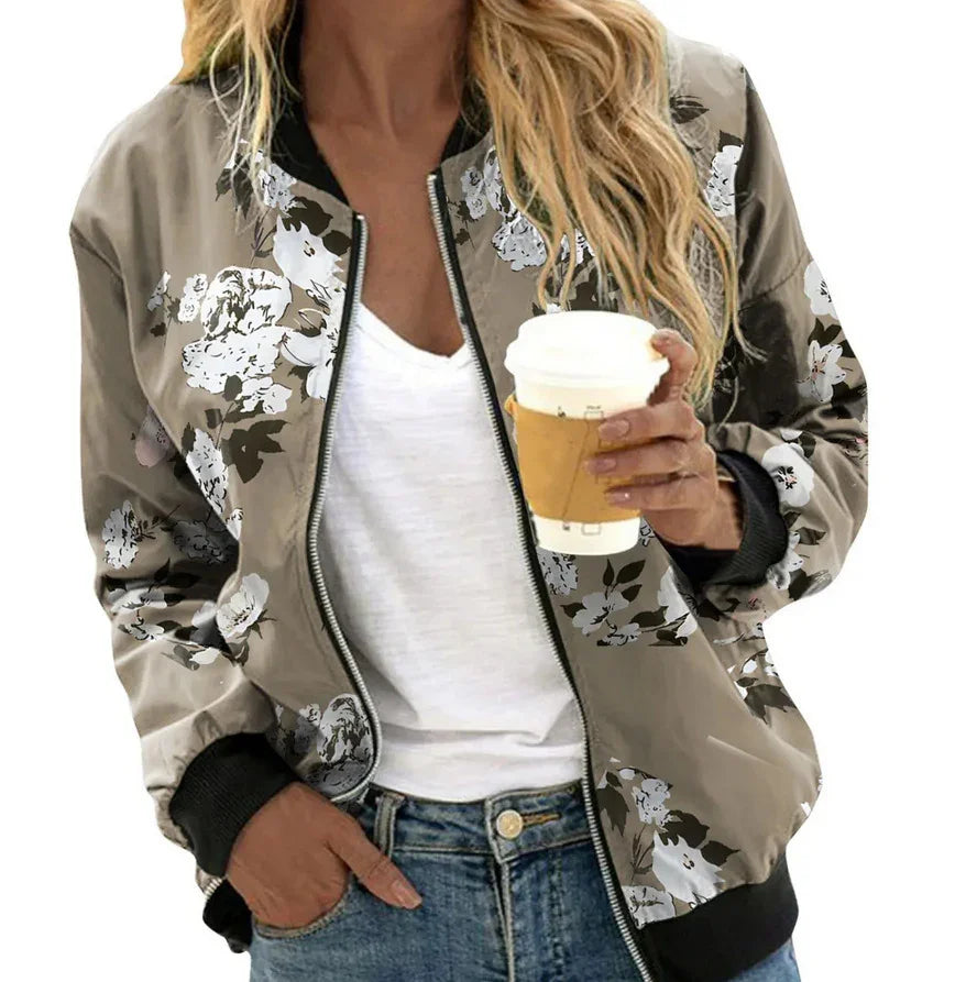 Woman wearing floral print bomber jacket over white shirt and blue jeans holding a coffee cup