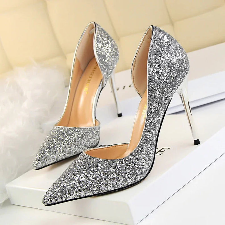 Pair of silver glitter pointed toe high heel shoes on white box in elegant setting