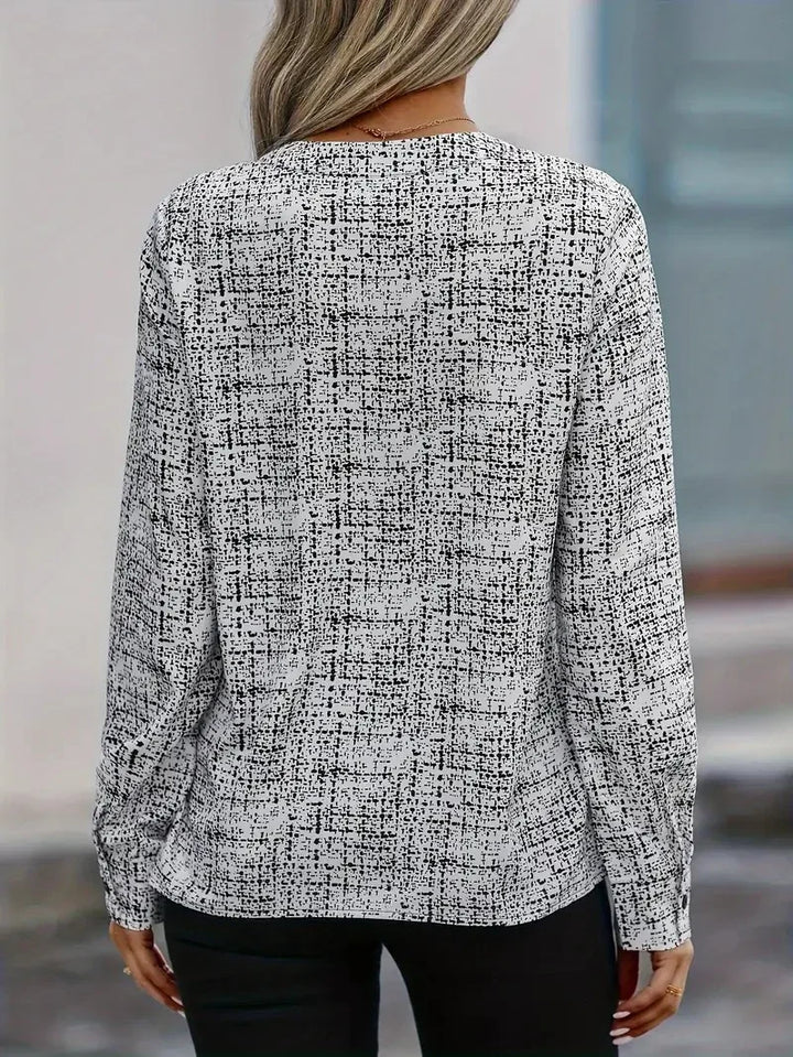 Woman wearing long sleeve black and white textured pattern blouse, back view