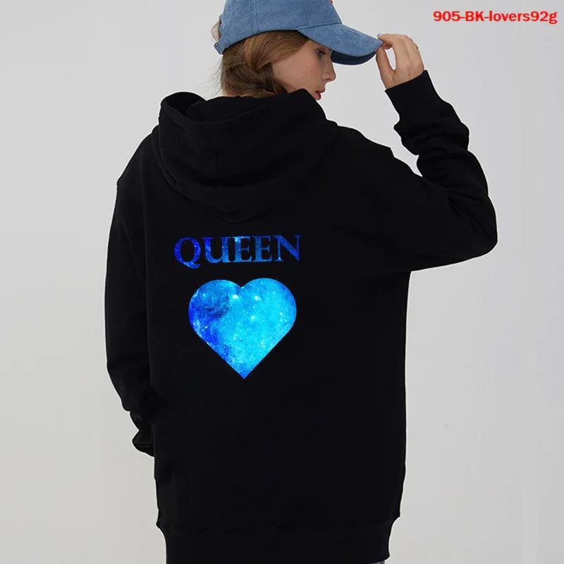 Woman wearing black hoodie with blue galaxy heart and QUEEN text, blue cap, studio background