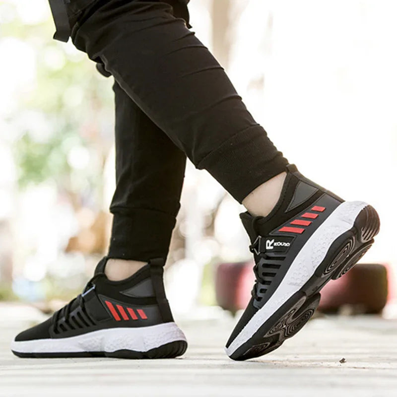Person wearing black and red athletic sneakers with white soles outdoors on pavement