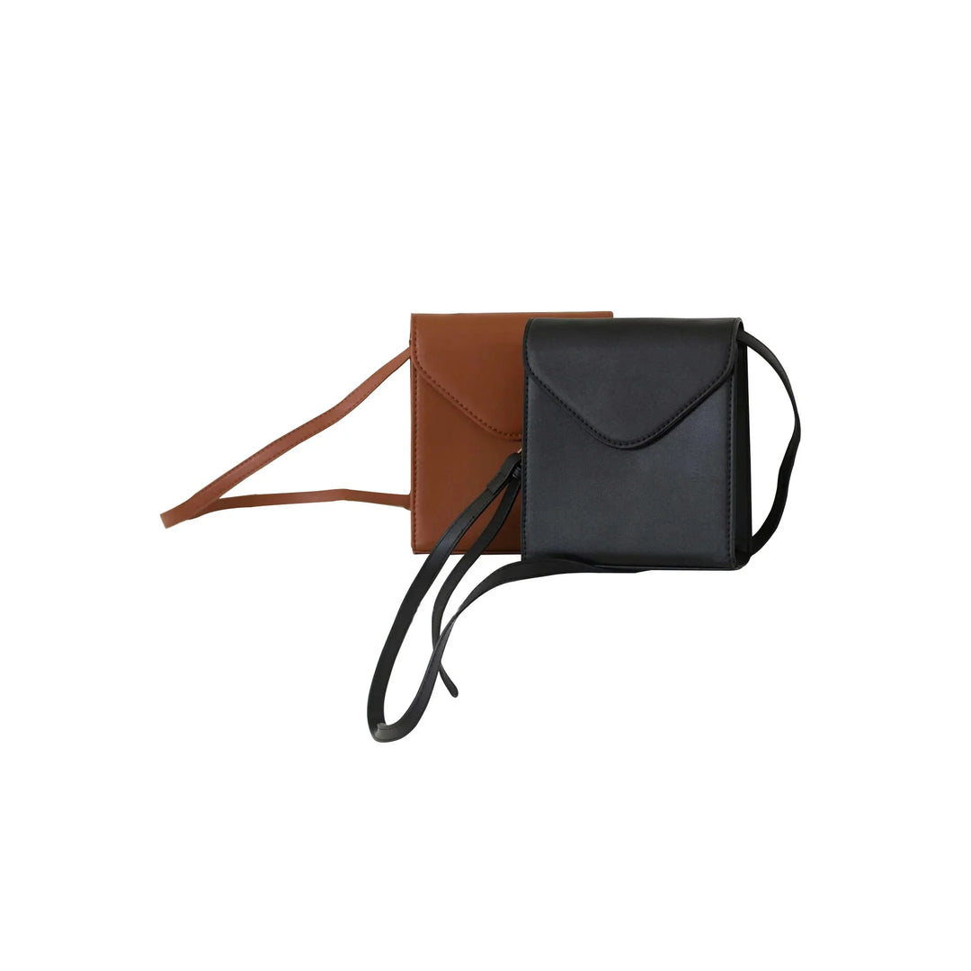 Minimalist black and brown leather crossbody bags with flap closures and long straps on white background