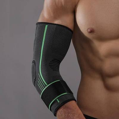 Man wearing a black compression elbow sleeve with green accents for arm support.