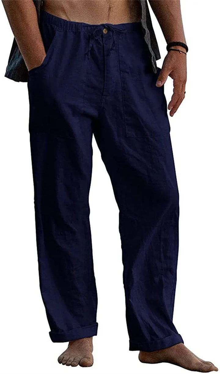 Man wearing navy blue relaxed fit cotton pants with pockets barefoot on white background