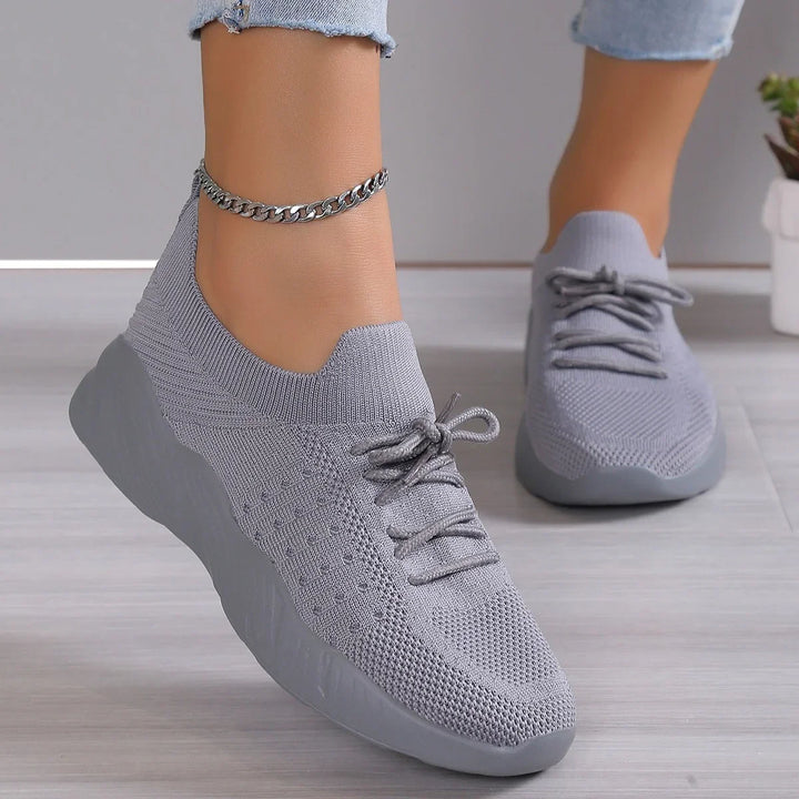 Light gray knitted athletic sneakers with laces worn with cropped jeans and silver chain anklet