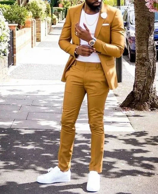 Man wearing mustard yellow slim-fit suit with white t-shirt and white sneakers on sunny sidewalk