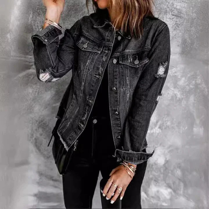 Woman wearing distressed black denim jacket with rolled cuffs, black pants, and gold bracelets