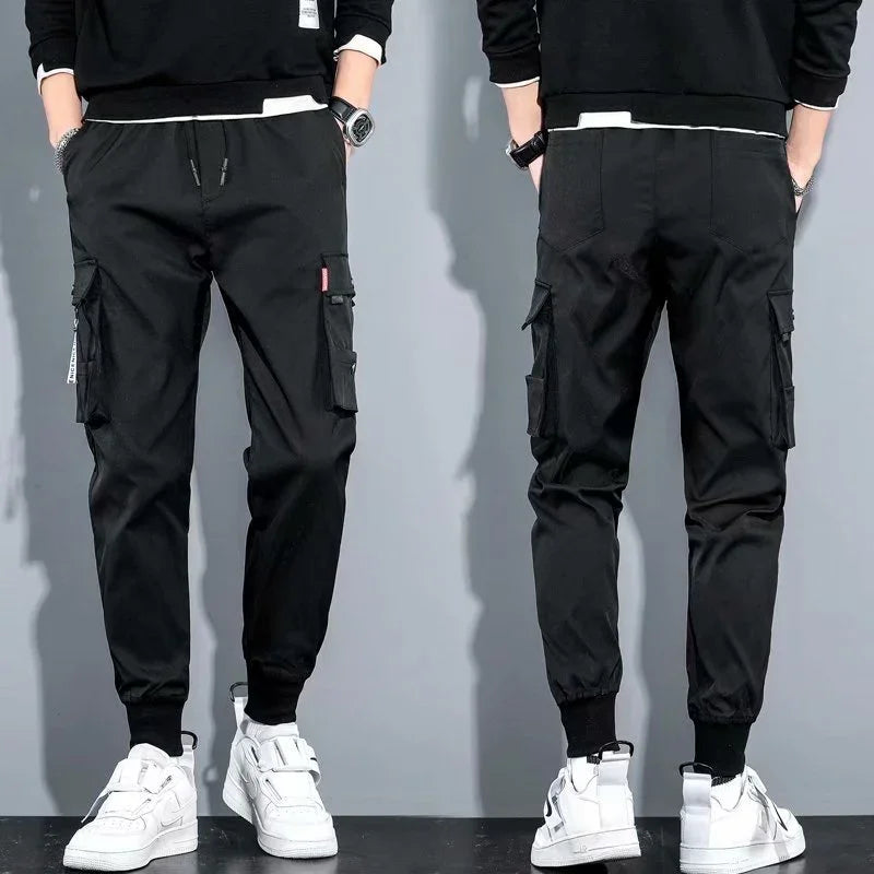 Front and back view of black cargo jogger pants with elastic cuffs and side pockets worn with white sneakers