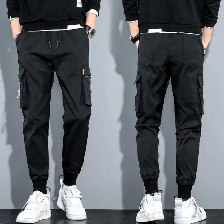 Front and back view of black cargo jogger pants with elastic cuffs and side pockets worn with white sneakers