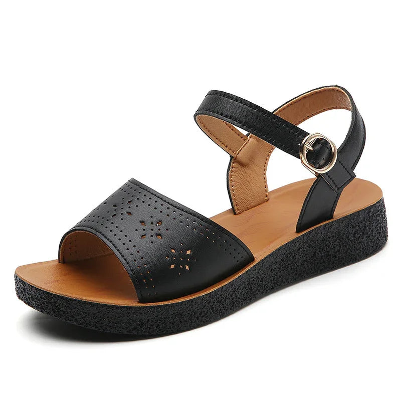 black women's wedge sandal with perforated floral design, adjustable ankle strap, and textured sole