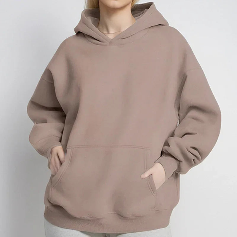 Woman wearing oversized beige hoodie with pouch pocket and relaxed sleeves on white background