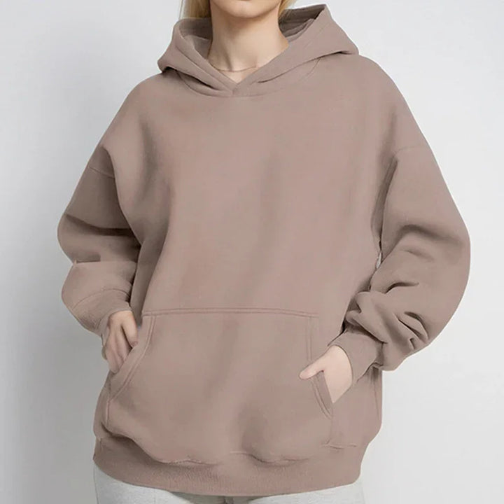Woman wearing oversized beige hoodie with pouch pocket and relaxed sleeves on white background
