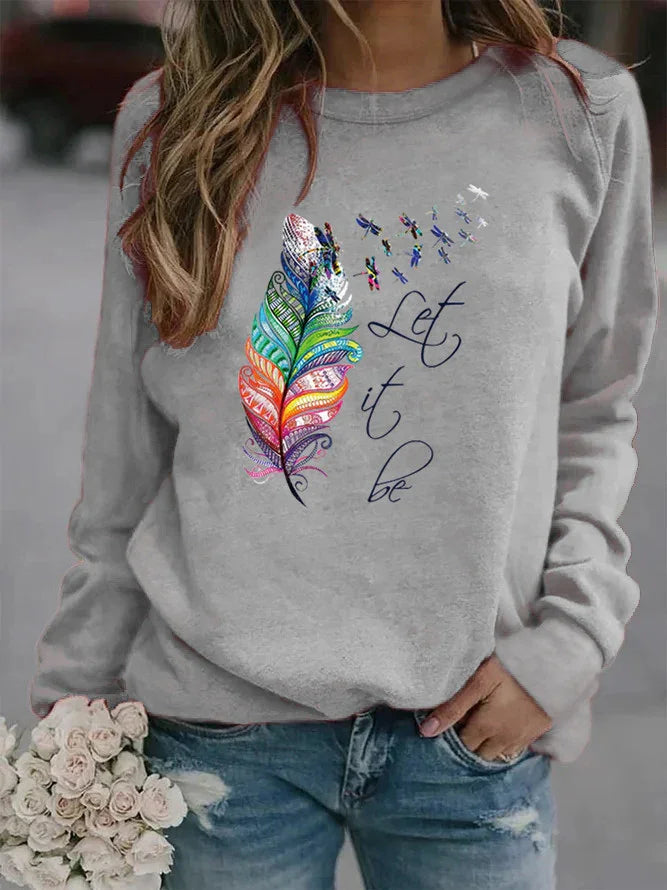 Gray sweatshirt with colorful feather and dragonfly print and 'Let it be' text, worn with blue jeans
