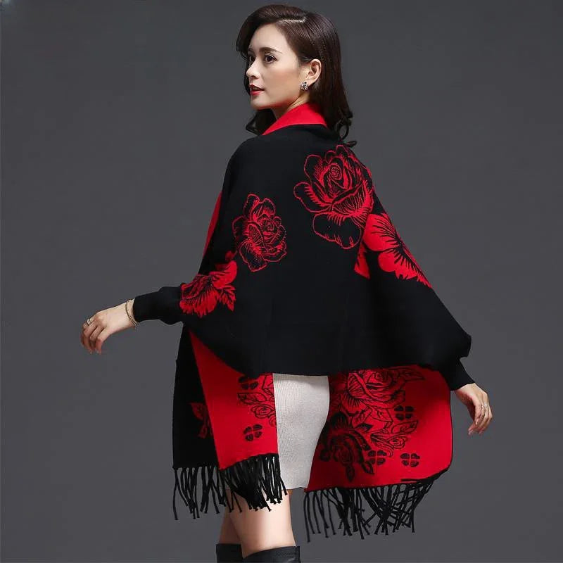 Woman wearing black and red floral shawl with fringe over white skirt against gray background