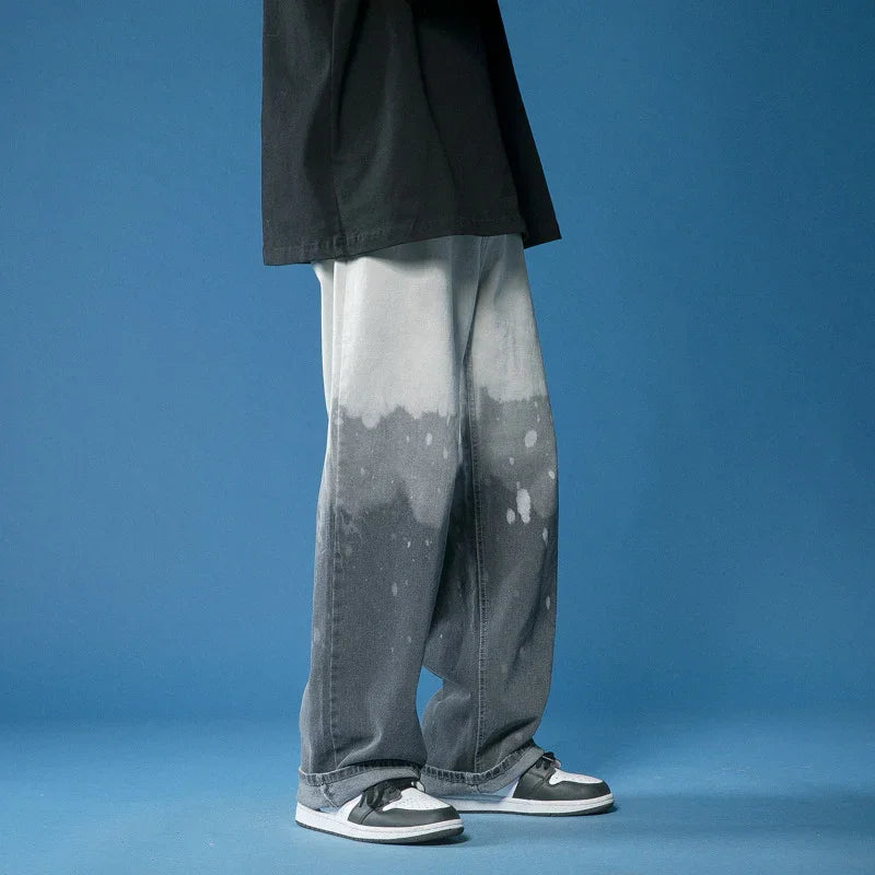 Person wearing black and white dip-dye jeans and black white sneakers on blue background
