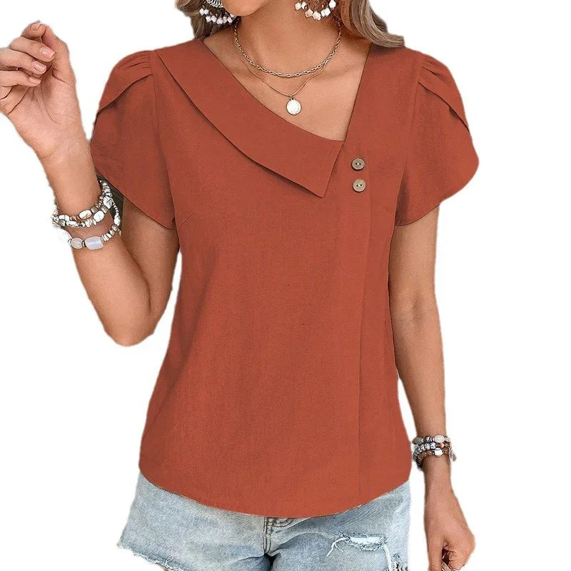 woman wearing rust orange short sleeve asymmetrical collar blouse with buttons and denim shorts