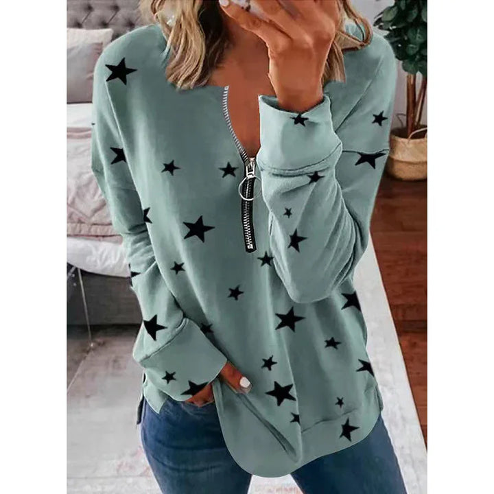 Woman wearing green star-patterned zip-up sweatshirt with front pockets, casual indoor setting